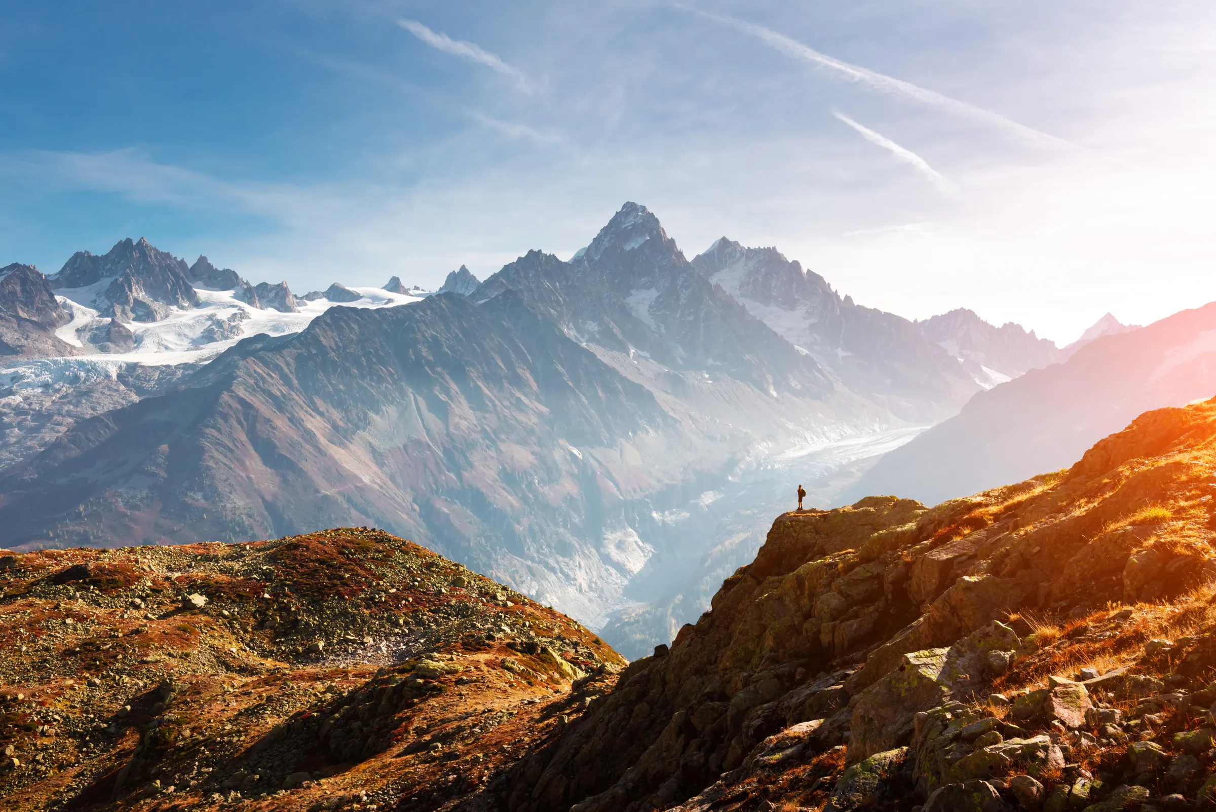 Lone figure on a ridge looking out over the Monte Bianco mountain range at sunrise