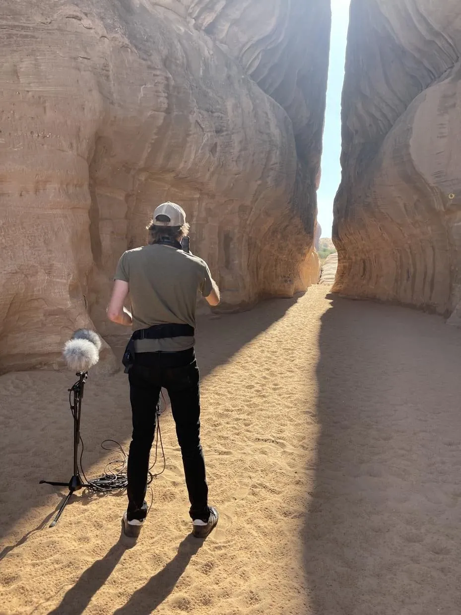 Field recordist capturing sound on location in a slot canyon