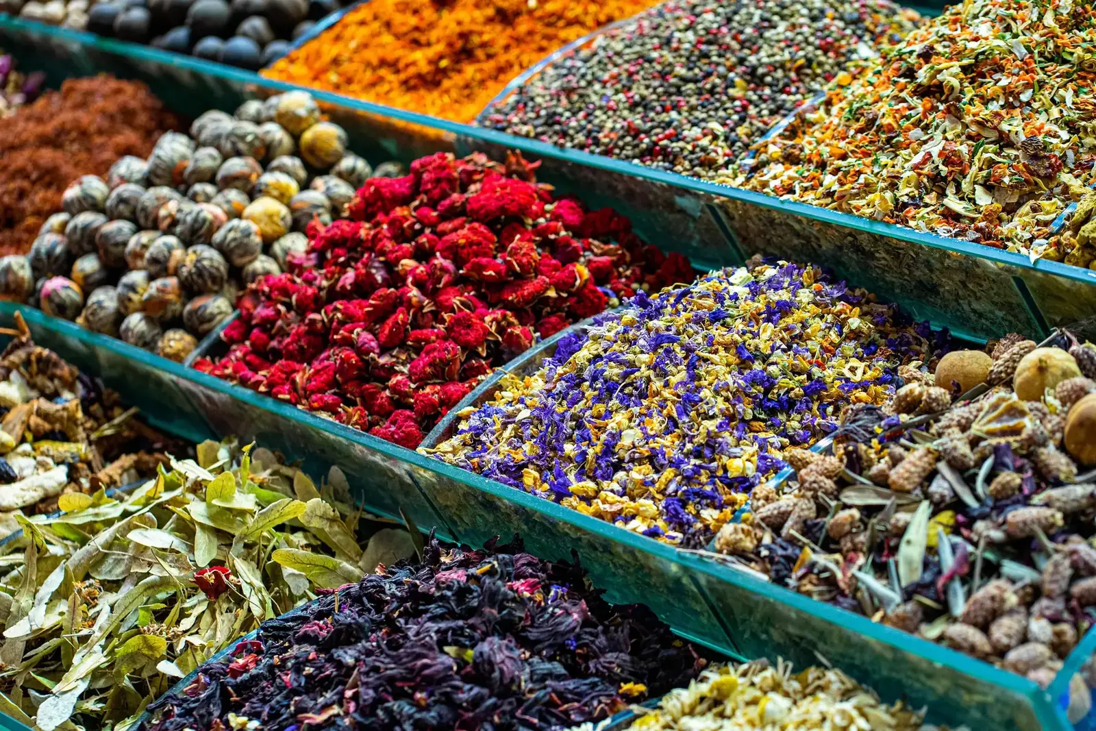 Colorful dried flowers, teas and spices piled high at a market stall